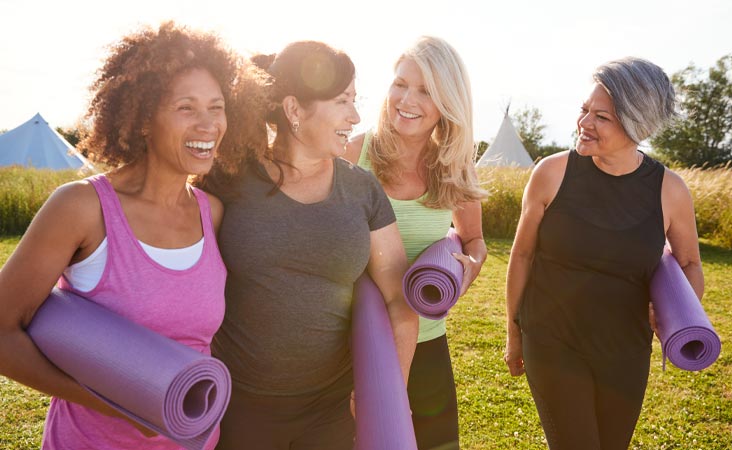 Group of older woman smiling together and holding yoga mats